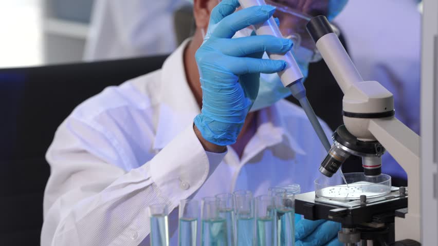 Team of Asian scientists working in modern laboratory equipped microscopes, chemical reagents, conducting advanced research in biochemistry, molecular biology, microbiology, pharmaceutical innovation