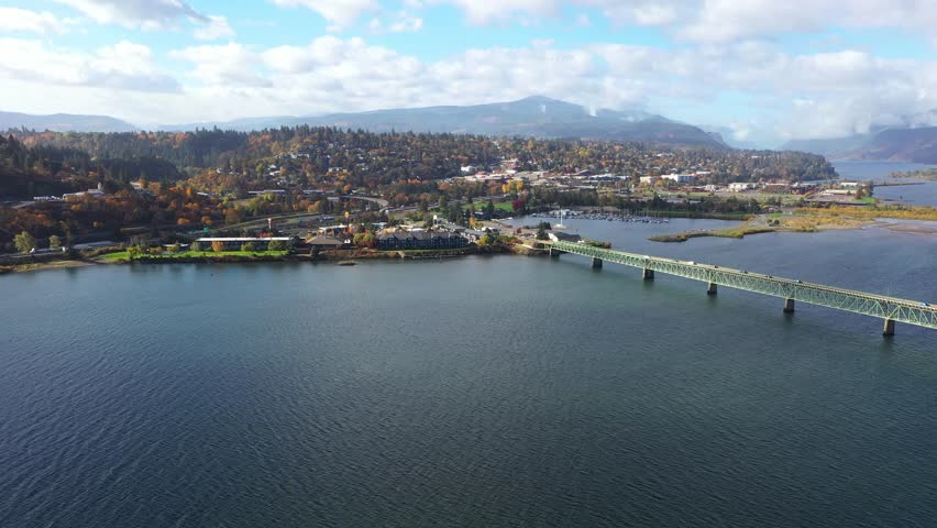 4K aerial drone footage of Hood River Bridge in Oregon showing light morning traffic on a sunny fall day. Scenic view of Columbia River with autumn colors and calm water in the Pacific Northwest 
