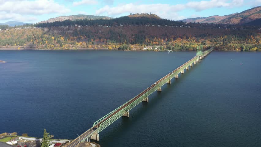 4K aerial drone footage of Hood River Bridge in Oregon showing light morning traffic on a sunny fall day. Scenic view of Columbia River with autumn colors and calm water in the Pacific Northwest 
