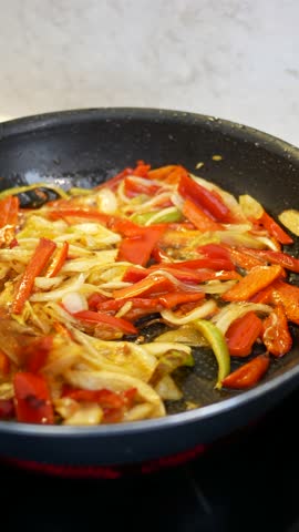 Cooking vibrant bell peppers and onions on a stovetop for a tasty dish.