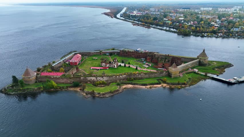 Drone shot of the historic Oreshek Fortress on a small island at the source of the Neva River with the town of Shlisselburg visible on the distant mainland shore