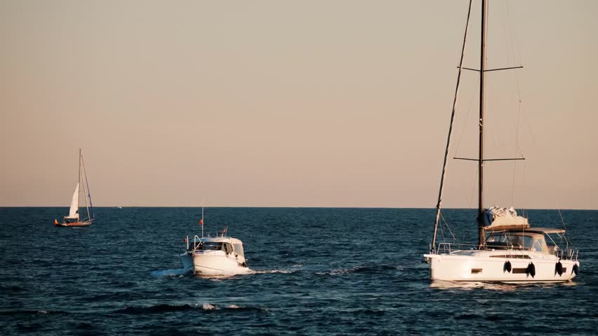 White boats moving calmly on the blue sea in Golfe-Juan, France, captured on a sunny day with scenic coastal views and peaceful Mediterranean vibes.