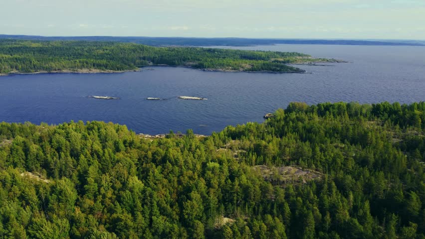 Russia, Lake Ladoga, Koyonsaari. View of the coast of the island in a cold lake. Beautiful nature of the Republic of Karelia. Panoramic view from the height of the Ladoga skerry islands. 4K