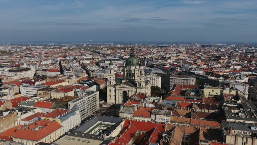 Expansive aerial showing St. Stephen’s Basilica standing tall amid the dense city grid of Budapest under a clear autumn sky.