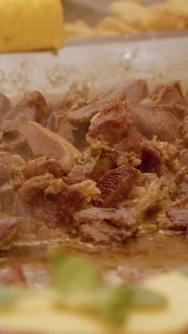 Vertical Screen Small pieces of meat cooking on a hot plate, releasing steam and juices, a typical street food scene