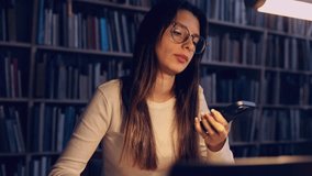 Side view of a student taking a phone call during study time at a library table, multitasking, communication and campus life themes. - Powered by Shutterstock - Get 15% off with code: PIKWIZARD15