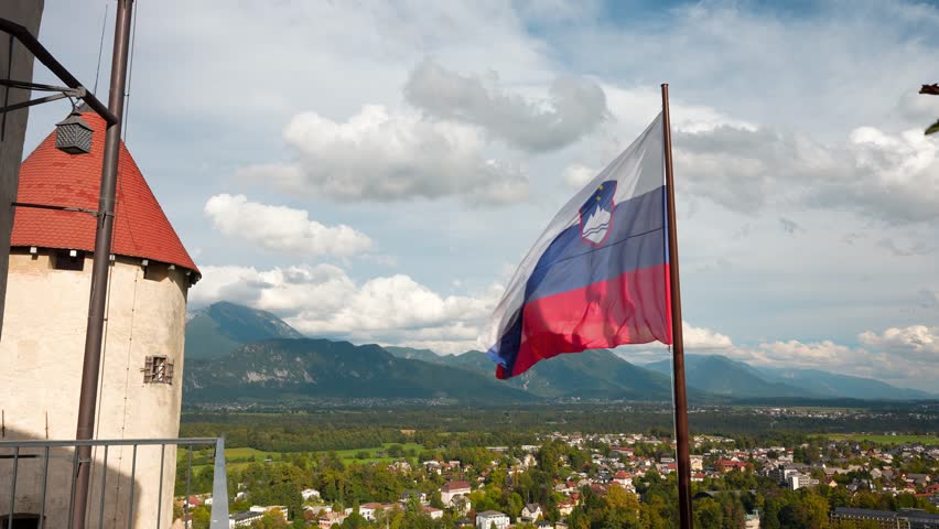 Medium shot of Slovenian flag waving in the wind at Bled castle during the day in Bled, Slovenia