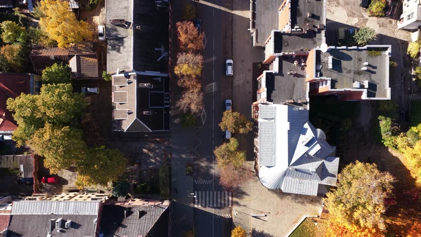 Drone image of Kaunas Old Town, featuring narrow medieval streets, red-tiled rooftops, and historic buildings surrounded by autumn foliage.