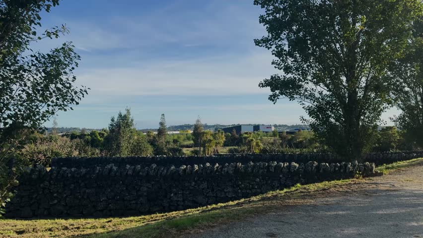 Old ruined short long stone walls built in public park.