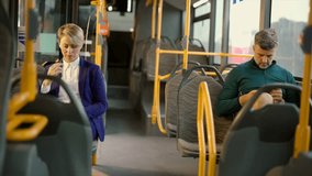 Commuters sitting separately inside a city bus, a businesswoman and a man, are absorbed in their smartphones while traveling, showcasing a common scene of modern urban transportation life - Powered by Shutterstock - Get 15% off with code: PIKWIZARD15