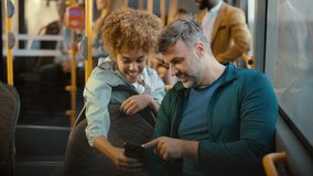 Happy diverse couple sitting on a bus, using a smartphone together, smiling and talking while browsing social media. A man and a woman enjoying their daily commute with modern technology - Powered by Shutterstock - Get 15% off with code: PIKWIZARD15