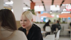 Smiling young lady with blonde hair interacts warmly with friend during relaxed cafe conversation, holding straw while laughing, expressing joy, connection, and lighthearted mood - Powered by Shutterstock - Get 15% off with code: PIKWIZARD15