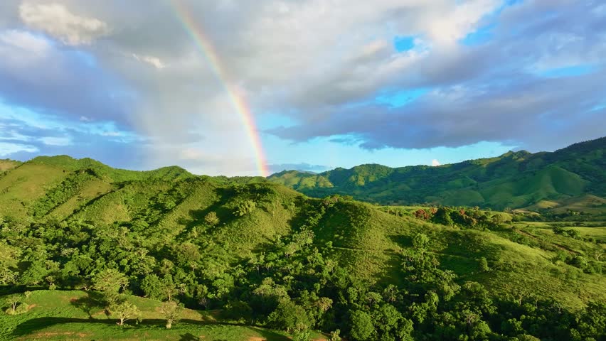 A vibrant rainbow formed during a short summer rain. Caribbean mountain landscape. Natural, open backdrop for travel. Beautiful scenery with forests, hills, and meadows in daylight. - Powered by Shutterstock - Get 15% off with code: PIKWIZARD15