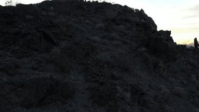 A dramatic silhouette of a lone man in a poncho, dressed as a spaghetti western hero, stands on a rugged mountain peak at sunset in the desert. The camera makes a pedestal up motion. - Powered by Shutterstock - Get 15% off with code: PIKWIZARD15