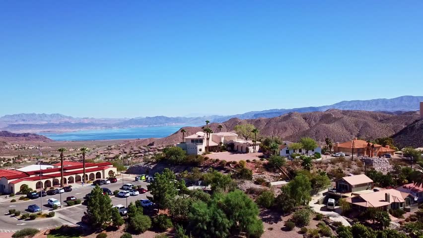 Drone above Boulder City Nevada tilting downward to reveal road in front of mountains and Lake Mead in the background