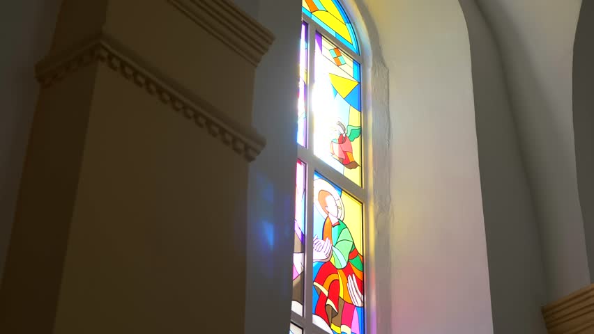 Sunlight streams through a vibrant stained-glass window, casting colorful patterns on the wall. Arched window with intricate stained glass illuminated by a bright sunbeam.	 - Powered by Shutterstock - Get 15% off with code: PIKWIZARD15
