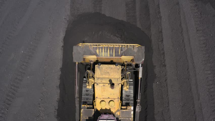 Aerial view of bulldozers directing coal at a thermal power plant for efficient energy production