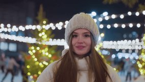 Happy woman in cozy winter outfit adjusting her beanie with a warm smile, bokeh holiday lights create a magical and festive atmosphere, capturing joy and warmth in a winter wonderland setting - Powered by Shutterstock - Get 15% off with code: PIKWIZARD15