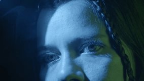 Dramatic close-up shot of a woman's intense gaze styled with bold lighting. Intricate braid captured under striking blue and green hues create a mysterious, contemplative mood. - Powered by Shutterstock - Get 15% off with code: PIKWIZARD15