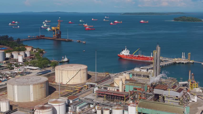 Expansive aerial view of the Rancha-Rancha Industrial Estate in Labuan, Malaysia, featuring the Petronas Methanol Plant and anchored oil tankers across the calm blue sea. Concept of energy production.