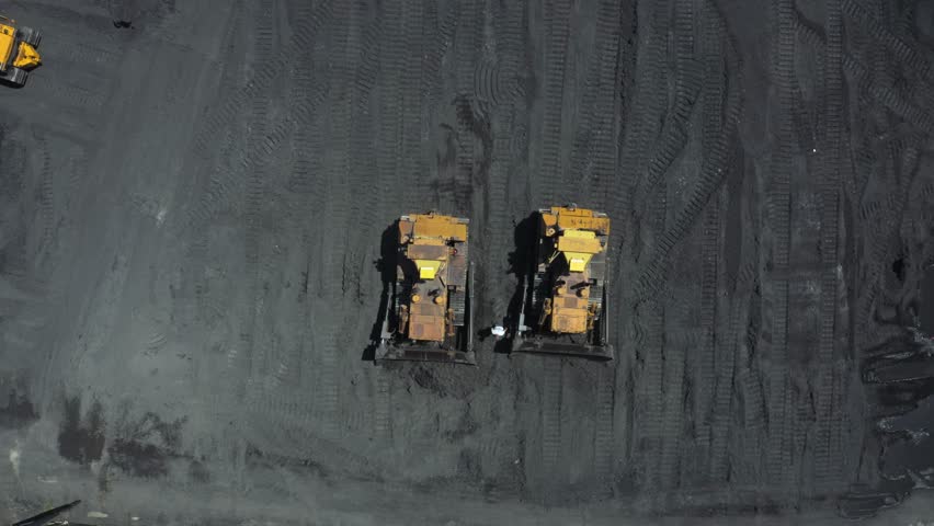 Aerial view of bulldozers moving coal at a thermal power plant during daylight operations for energy generation