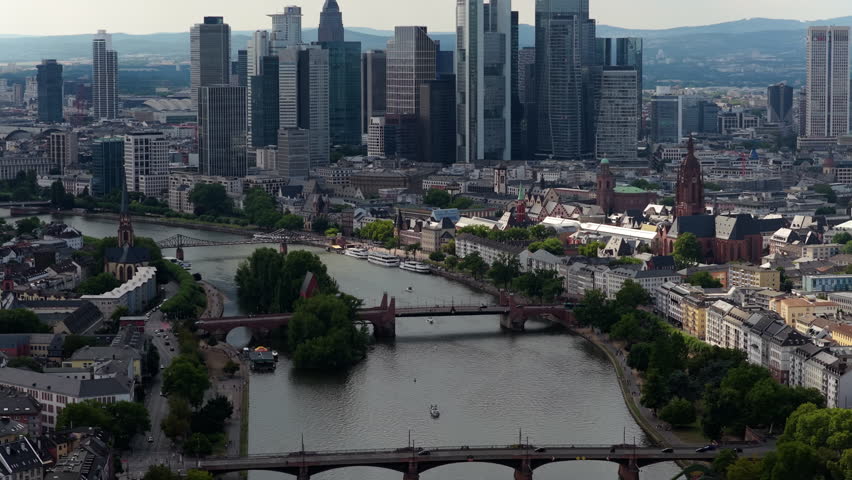 Aerial view flying over Main river towards financial corporation skyline of Frankfurt am Main in Hesse, Germany on a sunny day