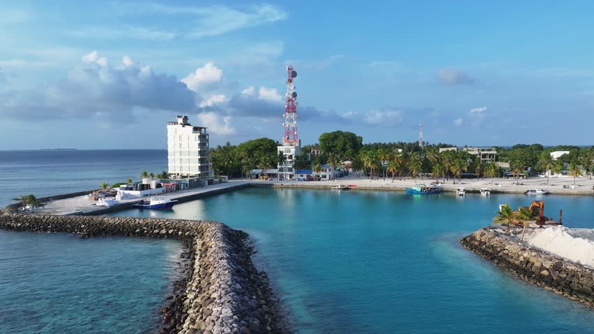 Aerial view of the serene Kamadhoo coastline, where turquoise waters meet white sandy beaches dotted with lush greenery, Kamadhoo, Baa Atoll, Maldives.