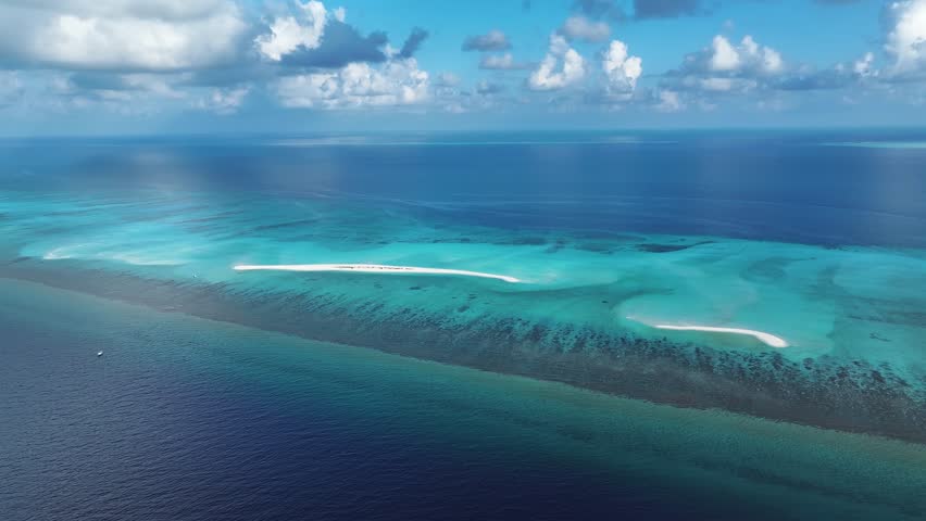 Aerial view of the sandbanks contrasts the turquoise waters with the deep blue ocean, a boat sits near the sandbank, Goidhoo, Baa Atoll, Maldives.