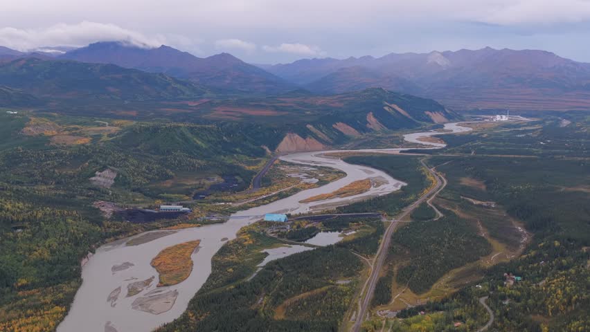 Aerial view of the winding Healy River snaking through the landscape with a power plant and mountains in the background, Healy, Alaska, United States.