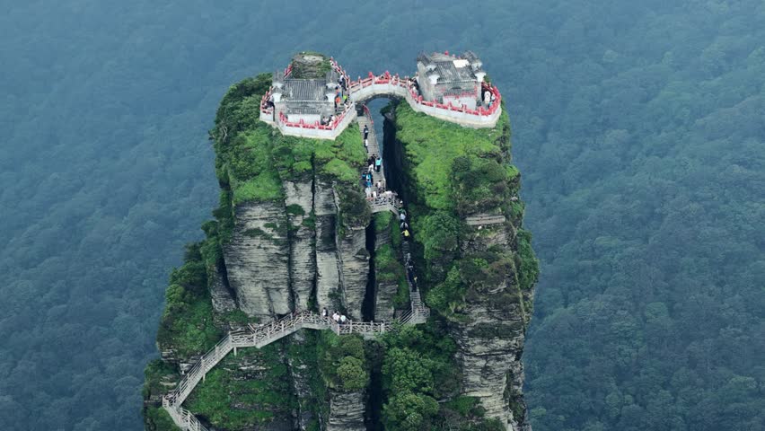 Aerial view of the Fanjingshan temples perched atop the dramatic rock formations, connected by bridges, amidst the lush greenery, Fanjingshan, Guizhou, China.