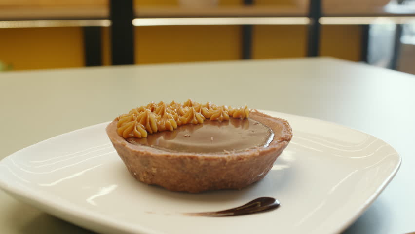 Panning shot of a chocolate cake adorned with fine peaks of dulce de leche, highlighting its texture and elegance.