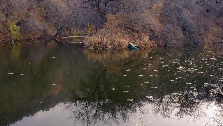 A natural landscape in late autumn with a sunken iron boat in a lake