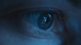 Close-up of a man eye watching or browsing on a smartphone, reflecting social media feed on iris at night, illuminated by blue light from a screen. Content consuming and social media addiction concept - Powered by Shutterstock - Get 15% off with code: PIKWIZARD15