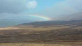 Natural landscape in Fuerteventura, Canary Islands  a dirt path through arid land facing the sea, with a colorful rainbow breaking through dramatic clouds. - Powered by Shutterstock - Get 15% off with code: PIKWIZARD15