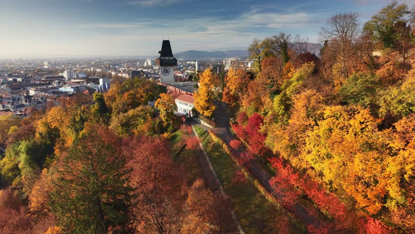 Autumn colors paint a beautiful landscape in Graz, Austria showcasing the stunning view of the city from Schlossberg hill. Aerial morning shot of Graz clock tower