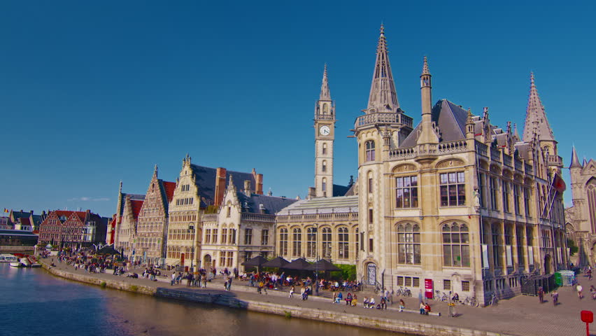 Ghent, Belgium - 15.08.2025: View of an old waterfront with traditional architecture and people strolling on a sunny summer day in the Flemish Region of Belgium. Timelapse