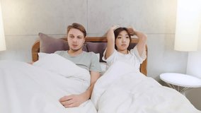 Worried multiracial couple in heated discussion in bed showing signs of disagreement and emotional tension in a modern bedroom setting - Powered by Shutterstock - Get 15% off with code: PIKWIZARD15