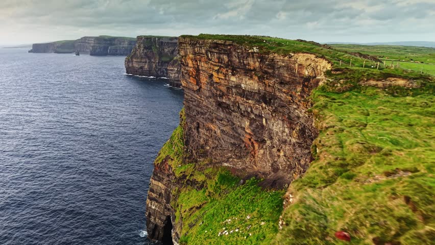 Aerial breathtaking cliffs of Moher in Ireland, County Clare. Flying over path near the edge of Cliff of Moher - one of the most popular tourist destinations in Ireland