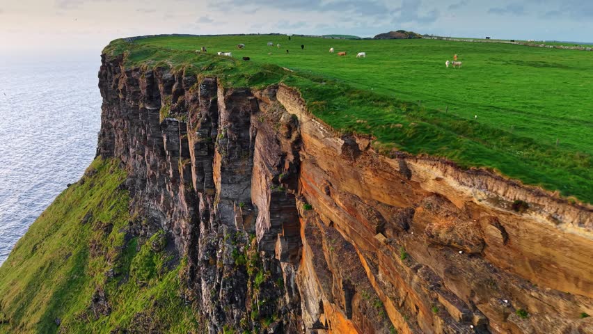 Flying along the edge in one of the most beautiful places in Ireland - Cliffs of Moher. Aerial coastal views along the Cliffs of Moher in Ireland featuring cliffs and Atlantic Ocean during sunset