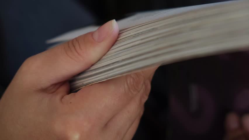 Flipping magazine pages quickly with hands, close-up lifestyle scene