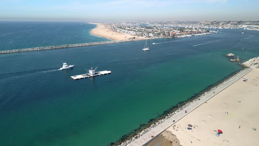 Wide aerial panorama of Newport Beach coastline with clouds over the Pacific Ocean long drone shot of sandy shore and scenic seascape in Orange County California USA relaxing summer view