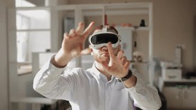 Young caucasian male experiencing virtual reality with headset in bright room. Man with VR headset surfs internet in browser with scaling gestures and shows gesture in office. - Powered by Shutterstock - Get 15% off with code: PIKWIZARD15