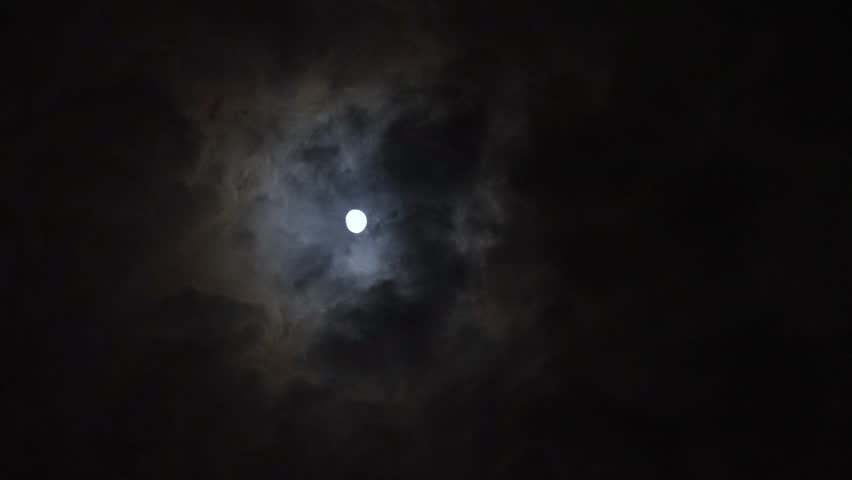 A view of the moon in the night sky as clouds pass in front of it