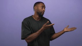 Man with open hands palms up gesture, wearing a black shirt and gold necklace, showing a visible ring in a purple studio setting; skepticism. - Powered by Shutterstock - Get 15% off with code: PIKWIZARD15