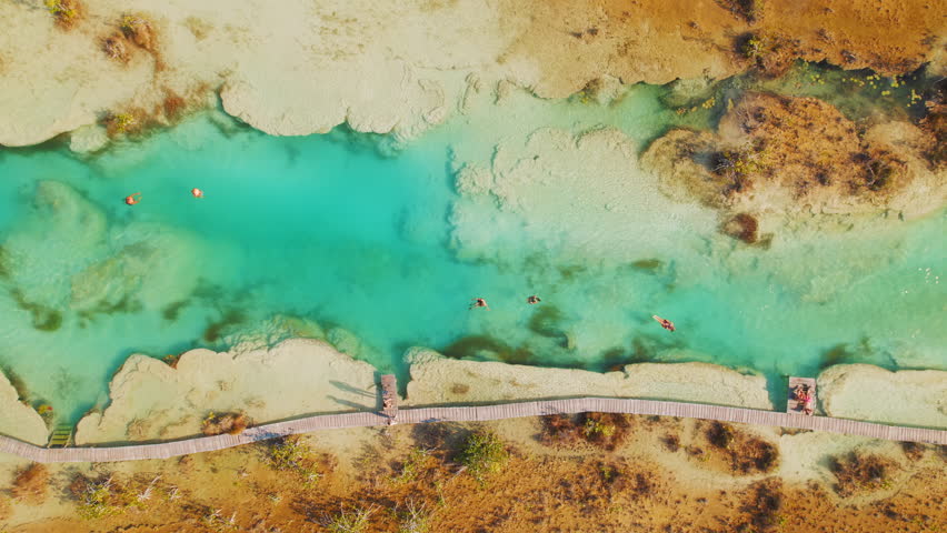 Top view of people floating in turquoise water canal in Bacalar nature reserve