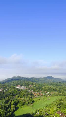 Peaceful hilly landscape under bright blue sky
