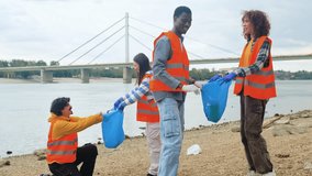 Group of volunteers cleaning river bank collecting plastic waste together. - Powered by Shutterstock - Get 15% off with code: PIKWIZARD15