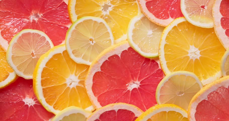 closeup of ripe juicy orange, grapefruit and lemon fruit slices, with water ripples top view. Bright, colorful and refreshing background for healthy food, beverages, diet, vitamin C and summer concept