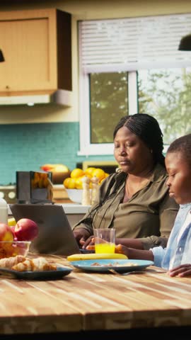 Vertical Video Children playing with food at table next to working mom focused on her career, ignoring her kids and family and solving her remote work on laptop. Little boy with mischief acting goofy