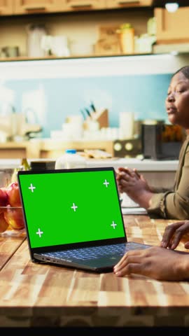 Vertical Video Mockup screen with African American family gathered for breakfast in the kitchen. Parents serve milk and orange juice while children enjoy granola and fruit, homemade meal at home